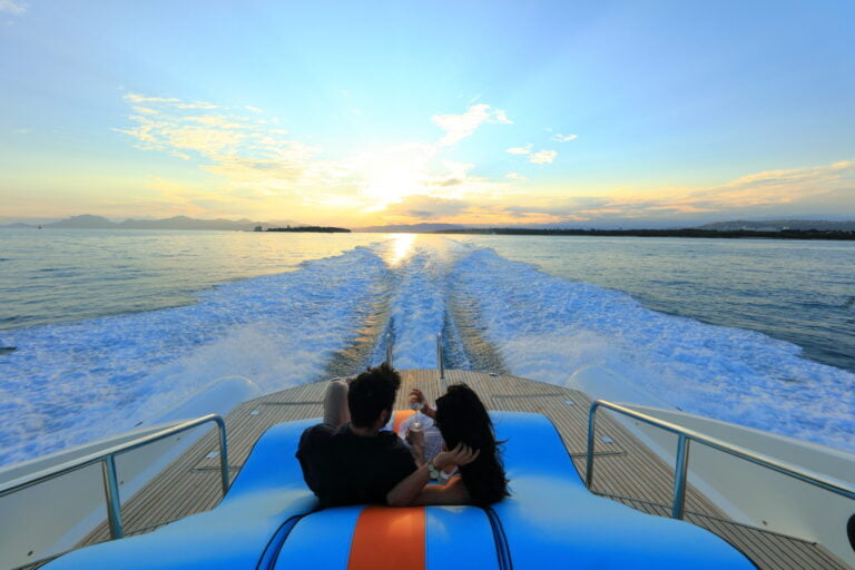 A cute couple hanging at the back of the boat looking at a beautiful sunset