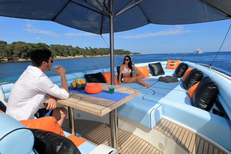 Two people hanging at the front of the boat, under a big umbrella casting a beautiful shadow